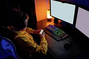 Using Phone Prints: Boy using smart phone while playing video game on table at home