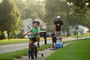 Small Group Prints: Two boys on bike and scooter; father pushes baby in a car, joyful
