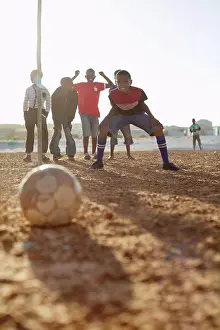 Pre Adolescent Prints: Boys playing soccer together in dirt field