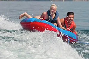 Fast Prints: Brett and Kali laugh as they hold on tight to the tube as it is pulled behind the boat