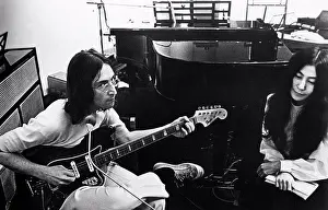 Guitar Prints: British singer, musician and member of The Beatles John Lennon playing guitar beside his wife