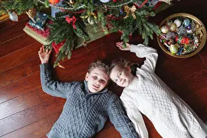 Sweater Prints: Brother and sister are lying on the floor under the Christmas tree