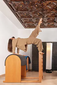 Instructor Prints: a brunette girl doing the bridge over barrel pilates pose with mask