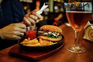 Knife Prints: Burger with French fries and Beer, fork and knife in male hands on wooden table background