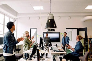 Connexions Prints: Business colleagues clapping for smiling speakers in office meeting