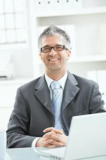 Businessman thinking Businessman sitting at office desk working on laptop computer