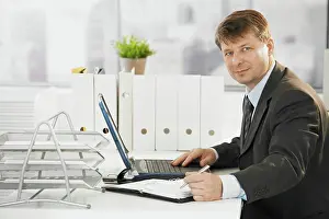 Notes Prints: Businessman using laptop computer Businessman working in office