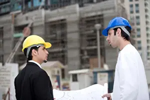 Professionalism Prints: Businessmen discussing blueprints at construction site, side view