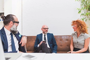 Consumer Electronics Prints: Businessmen and woman meeting on office sofa