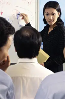 Businesswomen Prints: Businesswoman pointing to a pie chart on a whiteboard