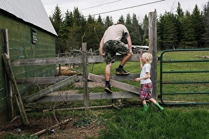 Kingston Prints: Canada, Kingston, Boy (8-9) assisting father climbing over fence in field
