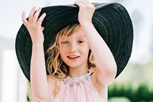 Expressive Prints: candid portrait of a young girl laughing playing with a large sun hat