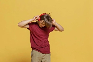 Yellow Background Prints: Carefree young man with headphones listening to music