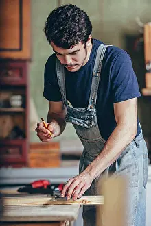 Manual Worker Prints: Carpenter marking on wood with pencil and ruler at workshop