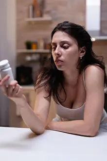 Migraine Prints: Caucasian woman with headache holding bottle of pills