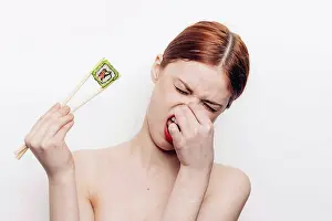 Tableware Prints: Caucasian woman holding sushi with chopsticks and holding nose