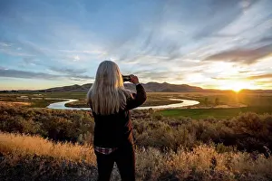 Baby Boomer Prints: Caucasian woman photographing sunset over winding river