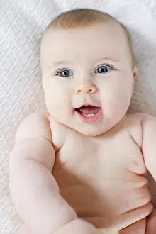 Cheerful baby with a brighteyed smile lies on a comfy white backdrop