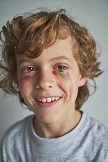 Paint Prints: Cheerful blond boy with fading rainbow under eye smiling looking away at home during quarantine