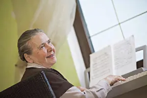 Arts Culture And Entertainment Prints: A cheerful senior woman playing an upright piano
