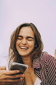 Connexions Prints: Cheerful young woman looking at smart phone held by friend at terrace