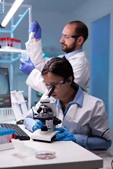 Examining Prints: Chemist researchers working in laboratory with micropipette and microscope