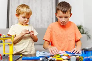 Smart Prints: Two children playing and building with colorful plastic bricks at the table