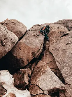 Groups Of People Prints: Climber ascending steep rock face with crampons secured by rope