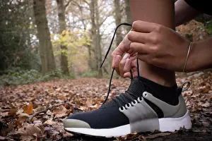 Runner Prints: Close up female runner tying shoelace in autumn woods