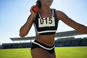 Sports Clothing Prints: Close up female track and field athlete throwing shot put