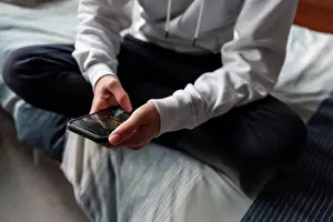 Sweater Prints: Close up of hands of teen boy in white sweater texting on phone