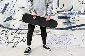 Skateboard Prints: Close up of unrecognizable young man holding longboard or skateboard in the park