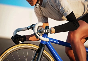 Disability Prints: Close-up of athletic woman with prosthetic arm riding bicycle