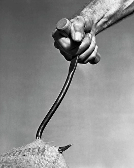 Gripping Prints: Close-up of a man's hand pulling a sack by a hook
