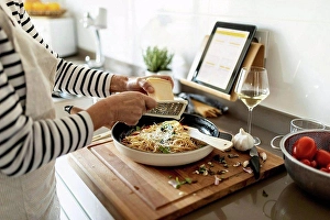 Best Prints: Close-up of woman with tablet cooking pasta dish in kitchen at home
