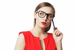2016 Prints: Close-up of young woman in glasses and red dress Pensive young woman in red dress and glasses holding pen