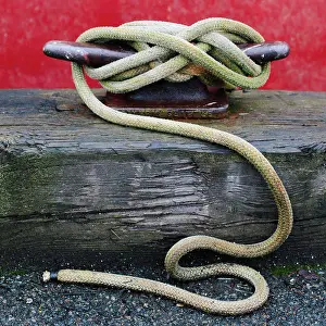 District Prints: Close up of a wharfside mooring cleat with a fishing boat rope tied around it