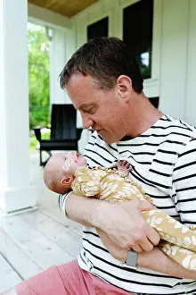 Parenting Prints: Closeup portrait of a dad holding his newborn baby daughter close