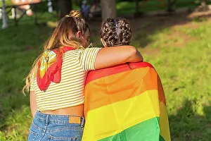 Assorted Prints: A closeup shot of two young Caucasian females holding LGBT pride flag outdoors