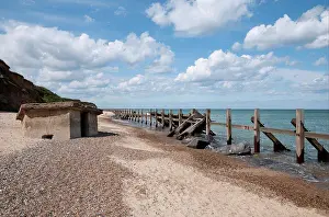 Coast Prints: Coastal defence groynes and upside-down World War Two pillbox on beach
