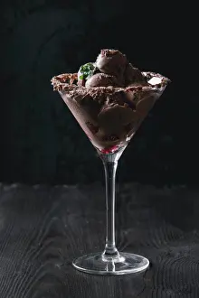 Refreshing Prints: Cocktail glass with chocolate ice cream mini balls with fresh raspberries and mint on black burnt wooden background