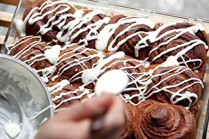 Cafe Prints: A coffee shop employee putting icing on a cinnamon rolls