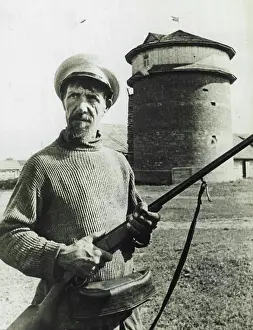 1941 Prints: Collective Farmer On Guard -- A collective farmer stands guard with his rifle before a stable