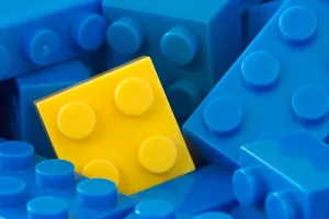 Plastic Prints: color toy background. yellow plastic brick in a middle of blue ones