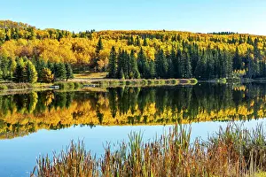Colourful Prints: Colourful hillside in the fall reflecting in a pond with blue sky