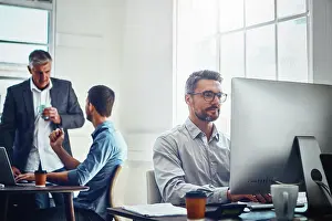 Focused Prints: Computer, work and businessman with his colleagues in the background talking