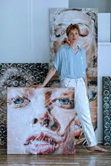 30 To 35 Years Prints: Confident mid adult female artist standing with various paintings in art studio
