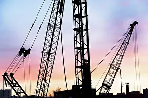 Beginnings Prints: Construction cranes at sunset