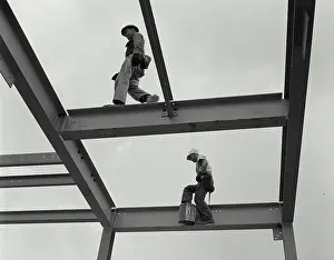 Full Length Prints: Two construction workers walking on the frame of a grain elevator