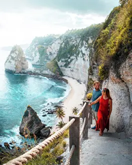 From Above Prints: From above of content couple in light summer wear smiling while going up rocky stairs on mountain along turquoise